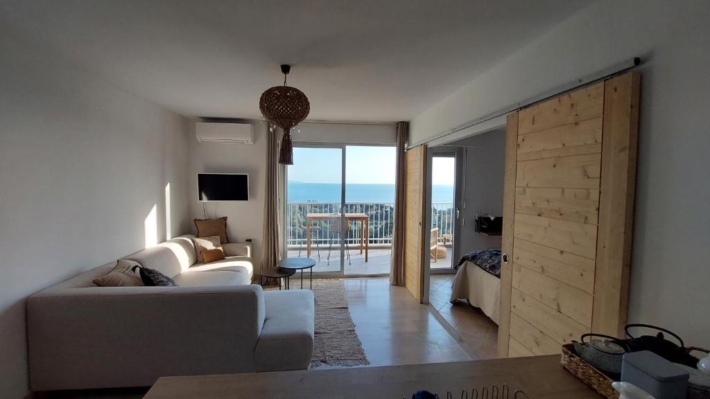 uma sala de estar com um sofá branco e uma porta de correr em Un balcon sur la mer em Ajaccio