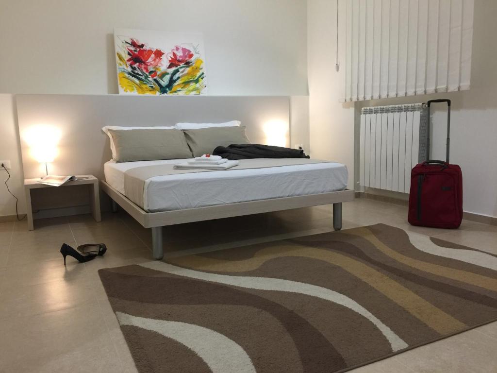 a bedroom with a bed with a red suitcase and a rug at Residenza DaMa in Lucera