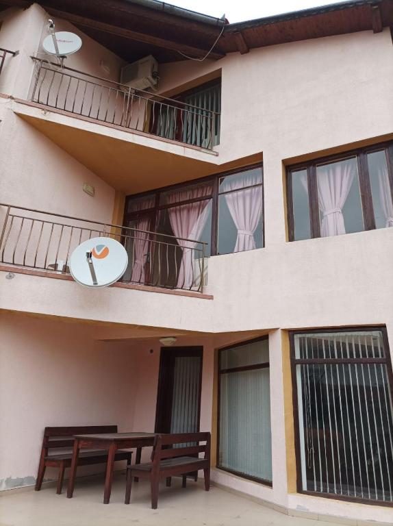 a building with two benches and a balcony with a surfboard at Villa Mars in Sunny Beach