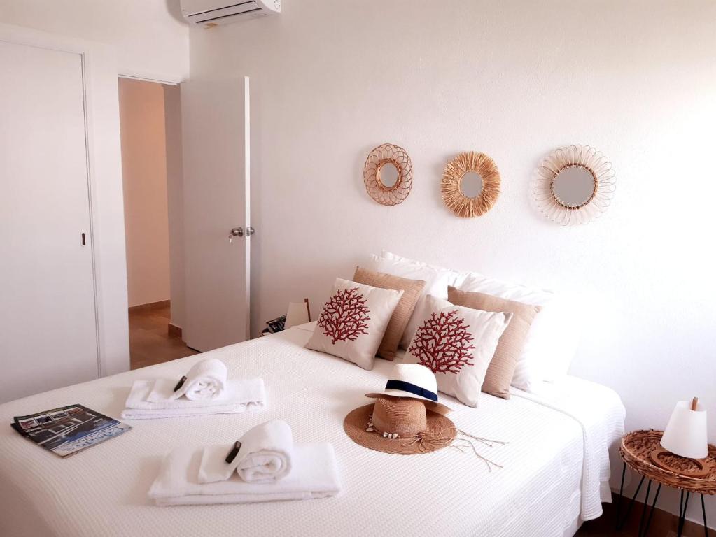 ein weißes Bett mit Handtüchern und Hüten darauf in der Unterkunft Beach Apartment Terrace in Vilamoura