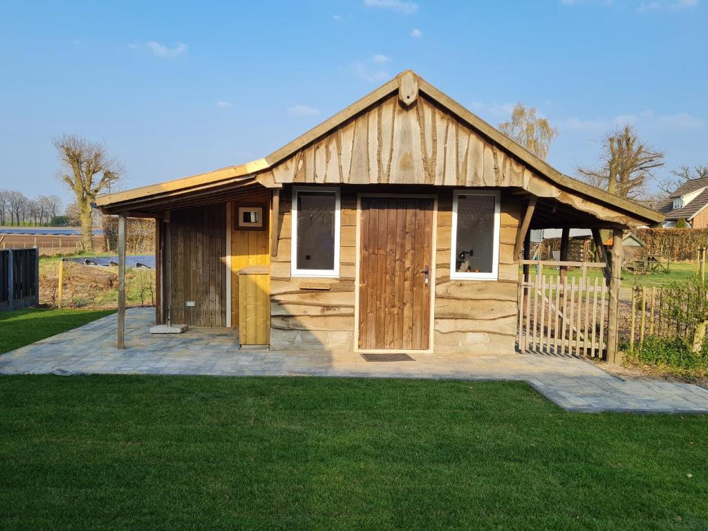 ein Holzgebäude mit einem Tor im Gras in der Unterkunft 't Hûske in Venhorst