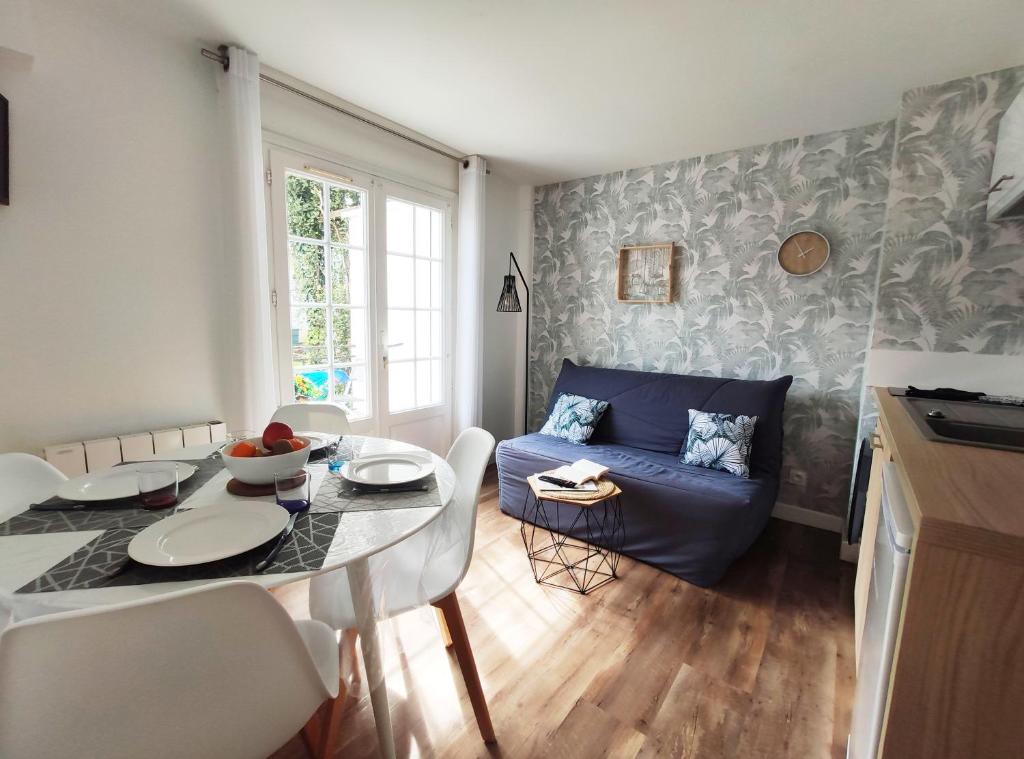 een woonkamer met een blauwe bank en een tafel bij Charmant T2 proche plage avec terrasse privative in Royan