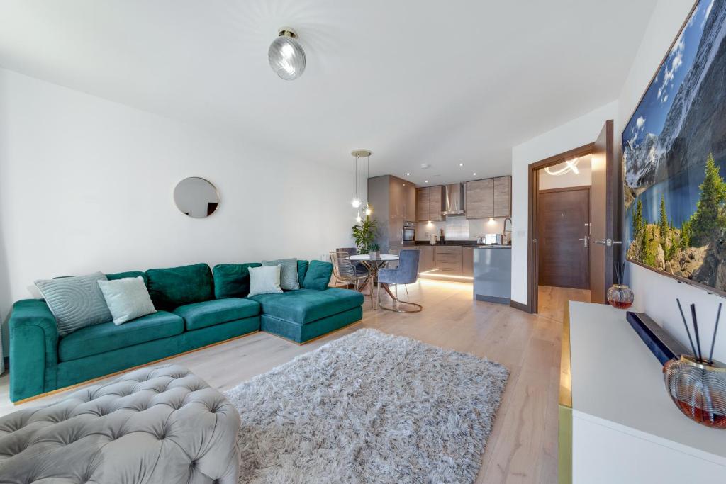 a living room with a green couch and a kitchen at Suites by Rehoboth - Darent Court - Dartford Station in Kent