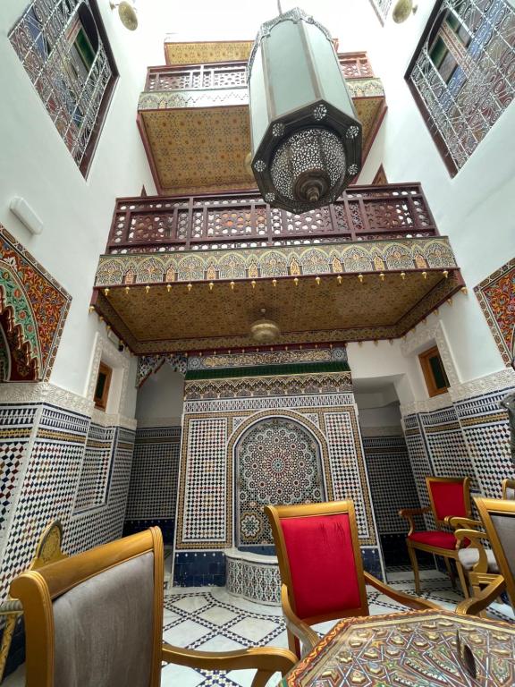 Habitación con una pared de mosaico con sillas y luz. en Riad Shama Fes en Fez