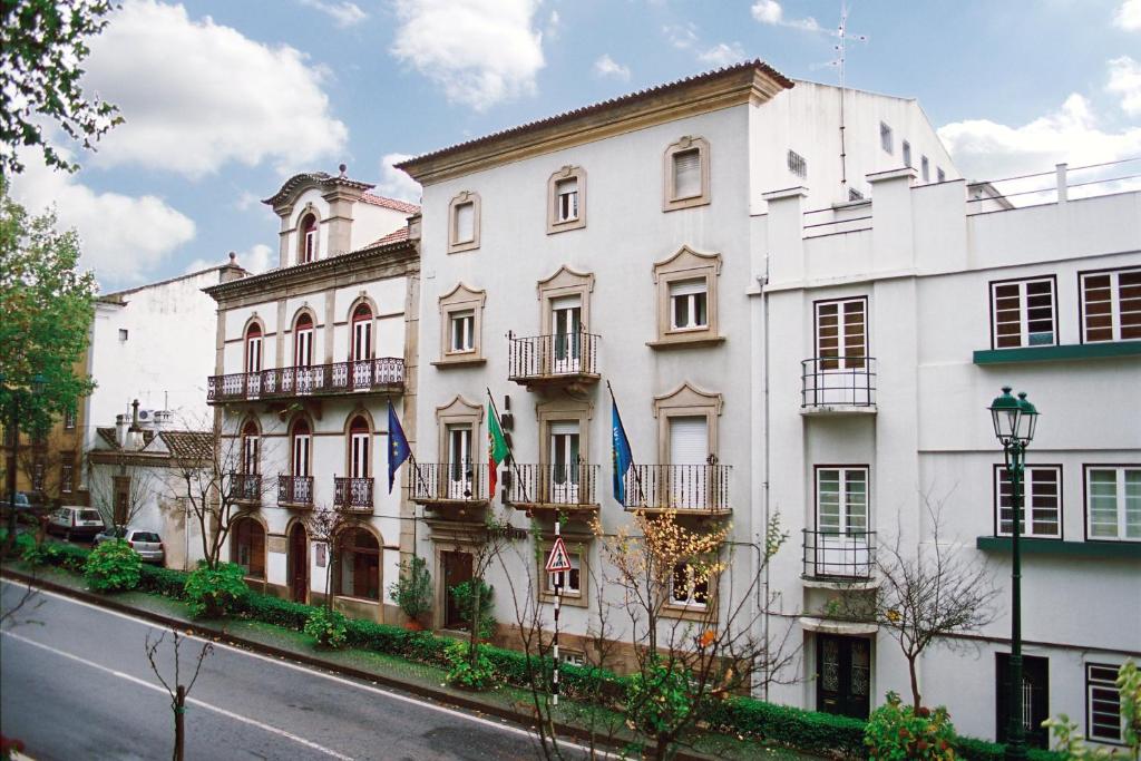 un edificio blanco con banderas delante en INATEL Castelo De Vide, en Castelo de Vide