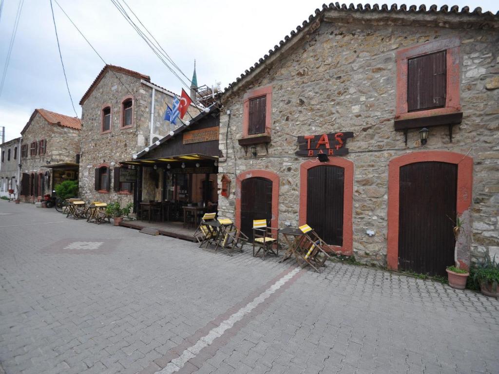 ein Backsteingebäude mit Tischen und Stühlen auf einer Straße in der Unterkunft Otel Yorgo Seferis in Urla