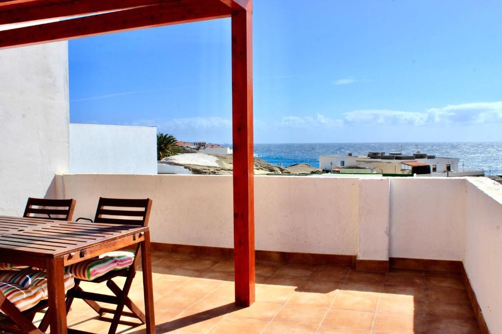 een balkon met een tafel en stoelen en de oceaan bij 3BDR Casa El Poris in Poris de Abona