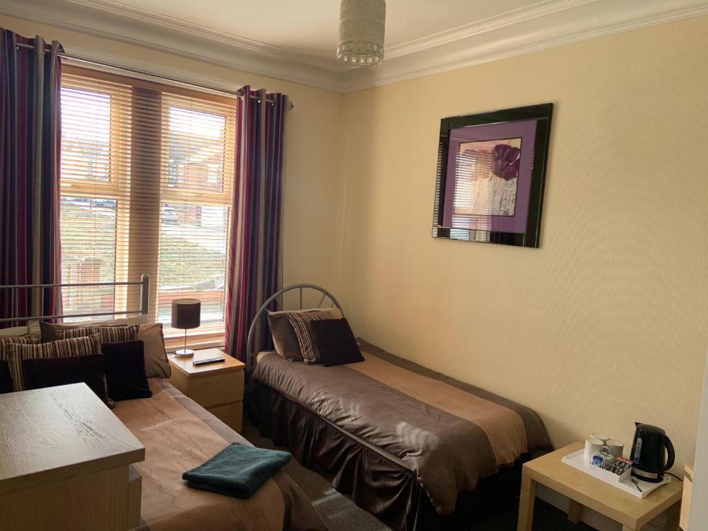 a hotel room with a bed and a window at Melrose Guest House in Whitley Bay
