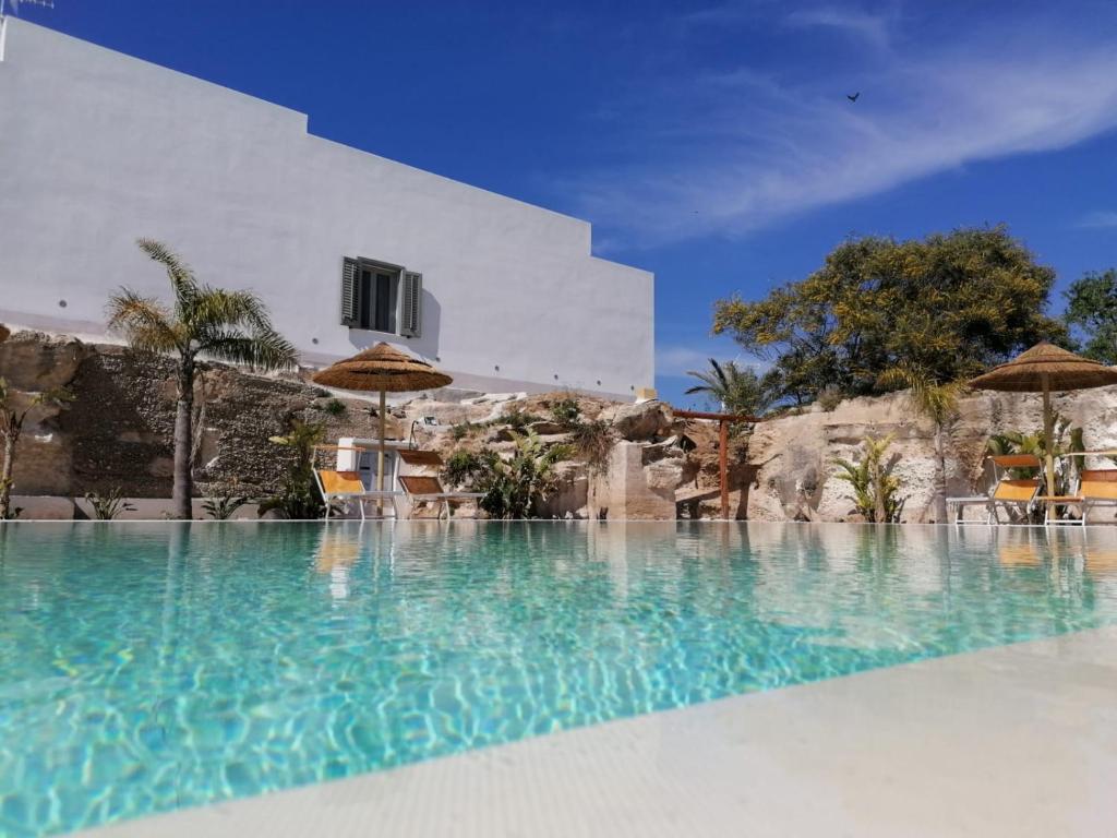 a swimming pool with blue water in front of a building at L'Oasi Villaggio Albergo in Favignana