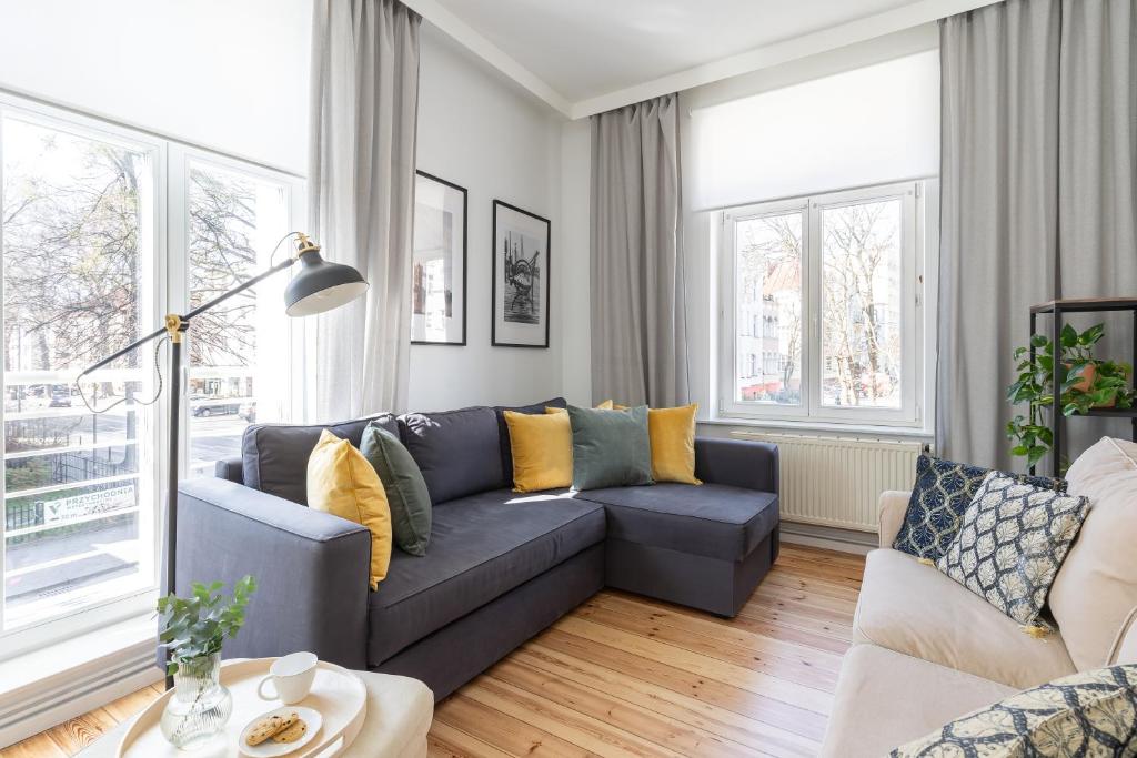 uma sala de estar com um sofá azul e almofadas amarelas em Lion Apartments - London em Sopot