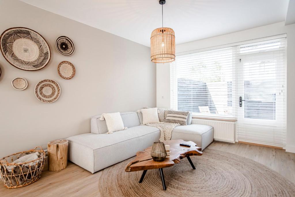 ein Wohnzimmer mit einem weißen Sofa und einem Tisch in der Unterkunft Marley’s Beachhouse - Luxury Apartment with garden in Zandvoort