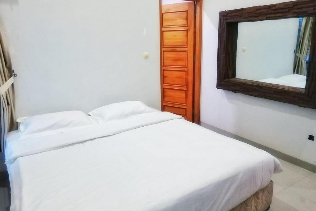 a bedroom with a white bed and a mirror at Tiray Homestay Syariah Yogyakarta Mitra RedDoorz in Salakan