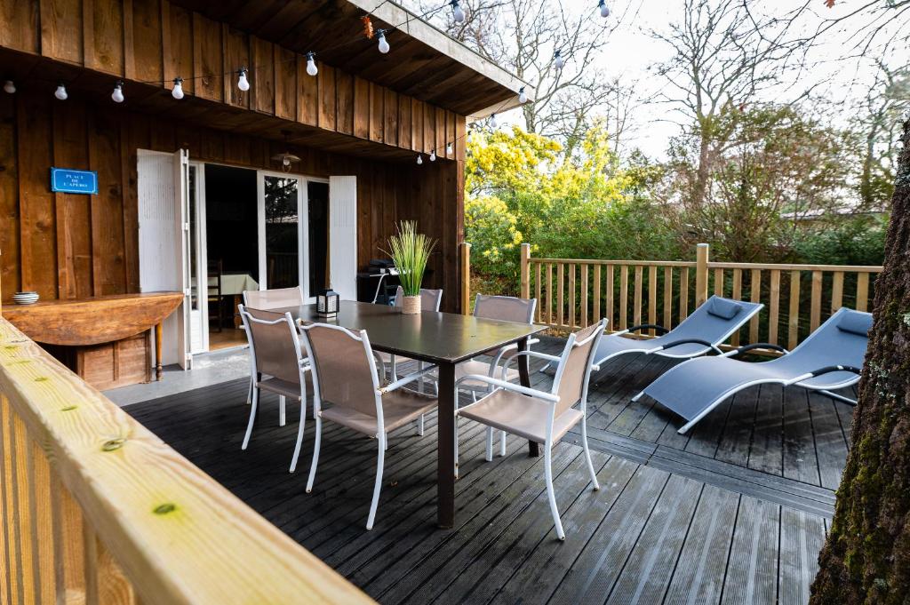 une terrasse en bois avec une table et des chaises. dans l'établissement LA PETITE MAISON DU LAC, à Biscarrosse