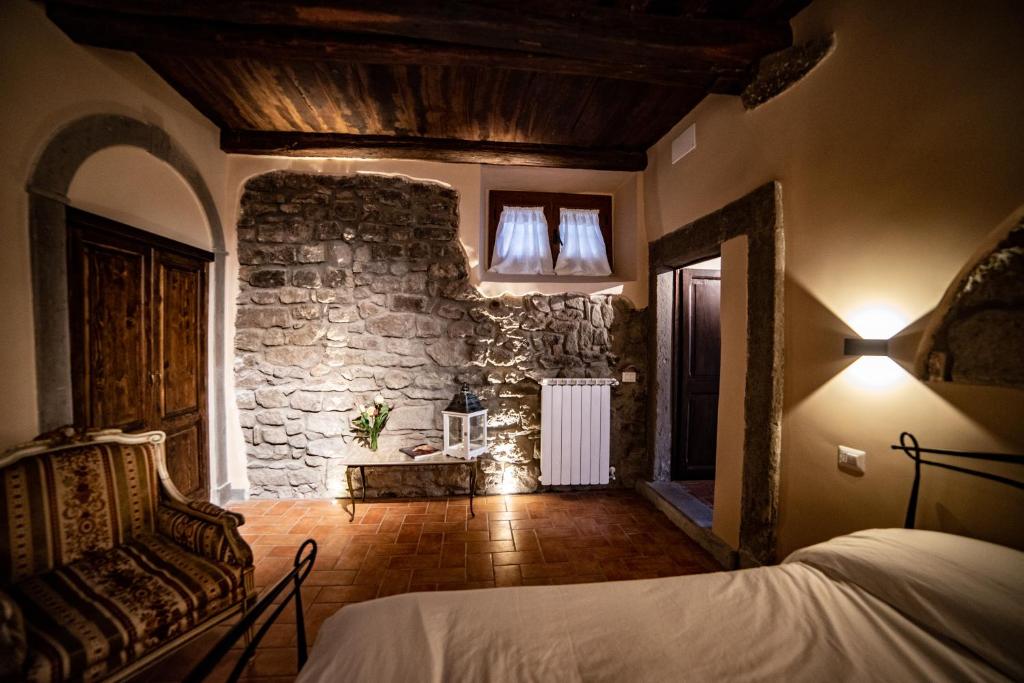 a bedroom with a bed and a stone wall at Il giardino nel borgo in Viterbo