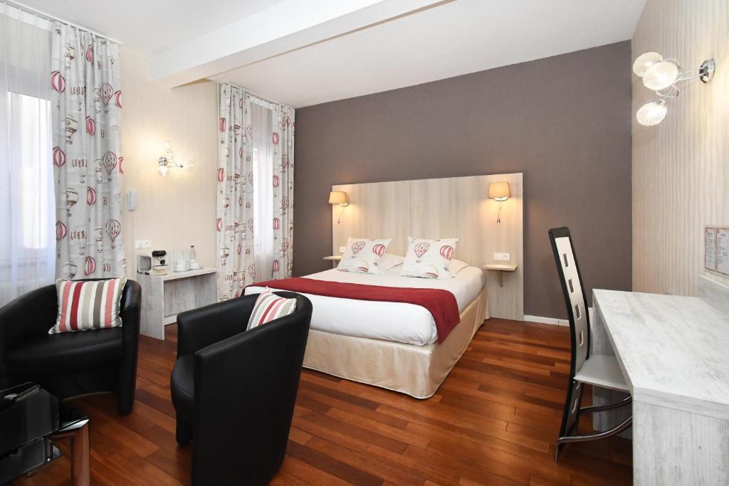 pokój hotelowy z łóżkiem i 2 krzesłami w obiekcie Logis Hôtel du Centre - Halte idéale en cyclotourisme avec garage à vélos clos w mieście Molsheim