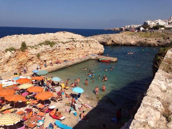 a group of people on a beach with umbrellas at Lungomare Modugno in Polignano a Mare