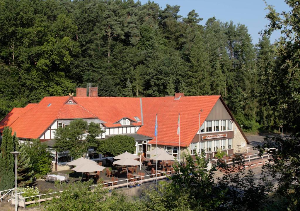 ein Gebäude mit einem orangenen Dach mit Tischen und Sonnenschirmen in der Unterkunft Ferien- und Wellnesshotel Waldfrieden in Hitzacker