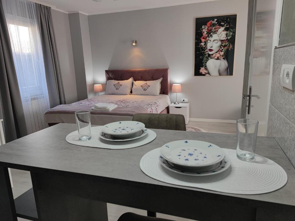 a room with a table with plates and glasses and a bed at Flora Apartment in Surčin