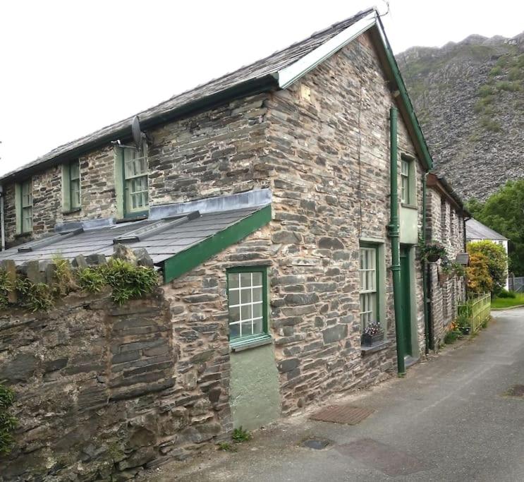 an old stone building with a green awning on it at Ty Hen in Blaenau-Ffestiniog