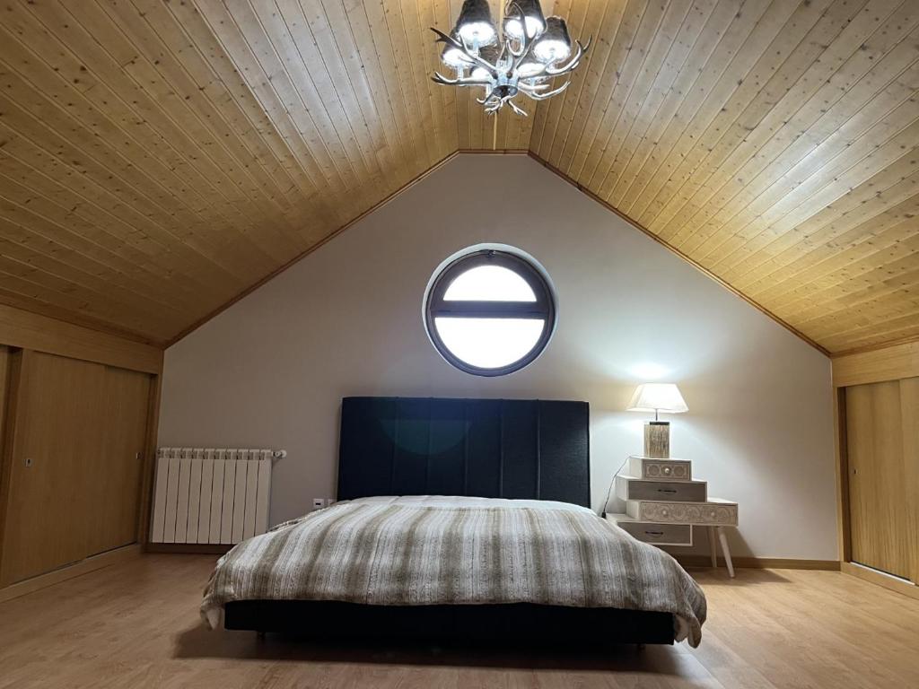 1 dormitorio con 1 cama grande y una ventana redonda en Estrela da Montanha, en Penhas da Saúde