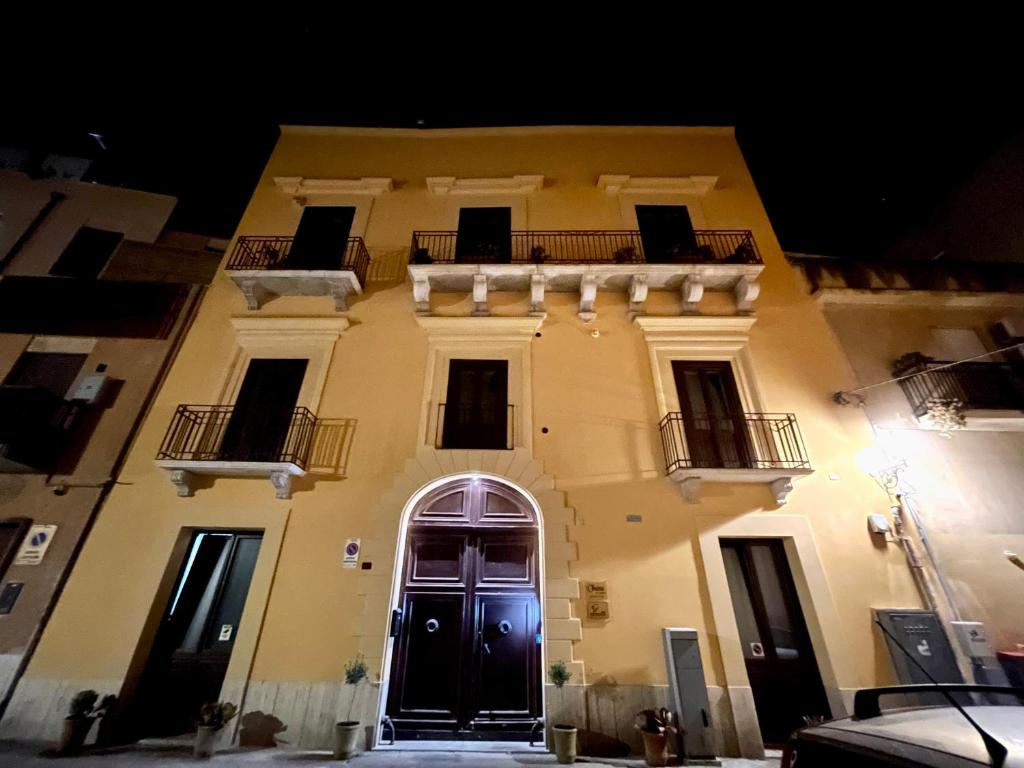 a large yellow building with a black door at Ohana by Casimiro in Trapani