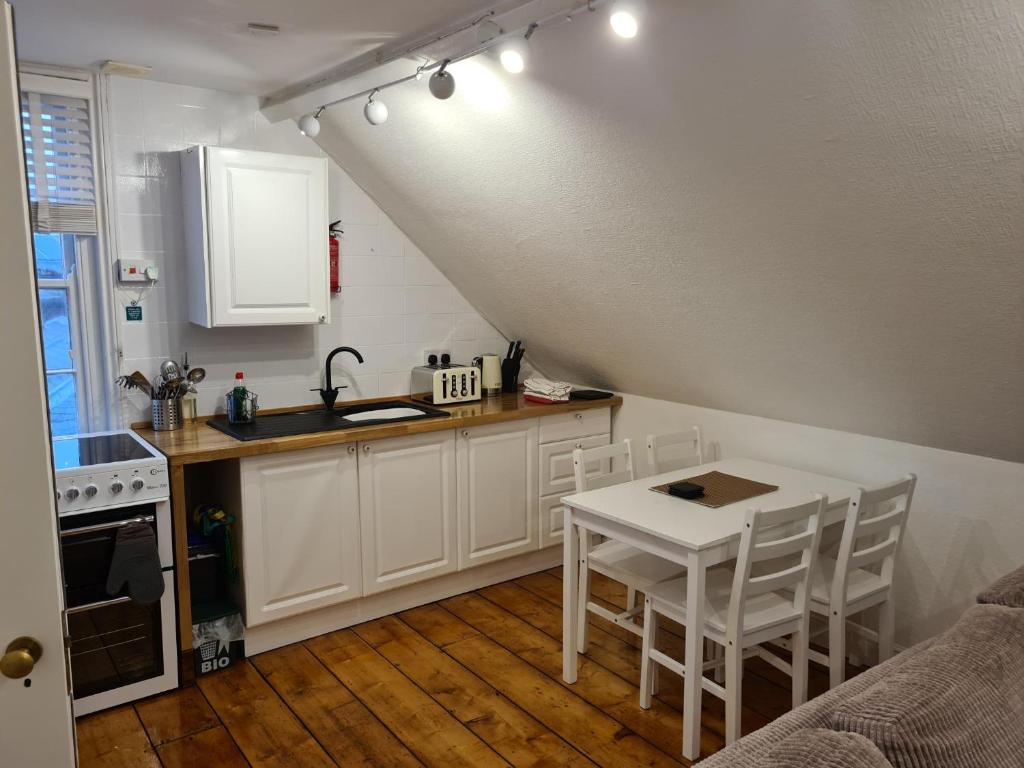 een keuken met een wastafel en een tafel met stoelen bij The Loft Apartment in Weymouth
