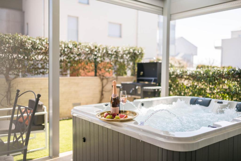 a hot tub with a bottle of champagne and a plate of fruit at Apt GioAn Novigrad, 500m to Sea, private heated Jacuzzi, BBQ, private parking in Novigrad Istria