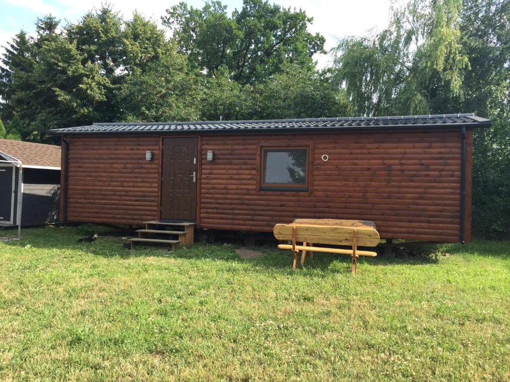 eine Holzhütte mit einer Bank im Gras in der Unterkunft Domek przy stawie in Nur