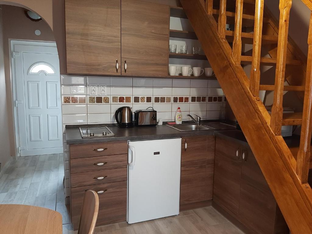 a kitchen with a white refrigerator and wooden cabinets at Egniss Apartman in Bogács