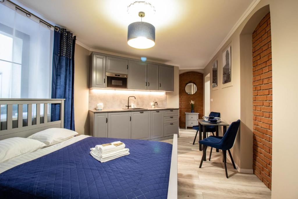 1 dormitorio con 1 cama azul y cocina en Nicolaus Apartment, en Toruń