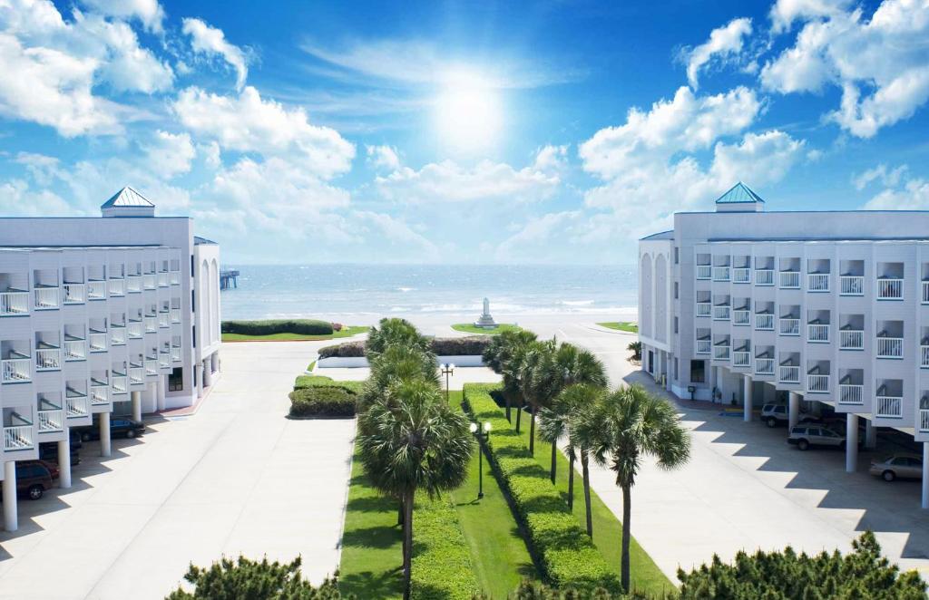 a view of two buildings and palm trees and the ocean at Casa Del Mar Beachfront Suites in Galveston