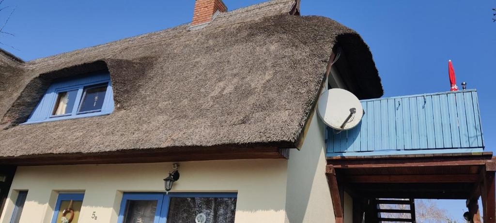 a thatch roofed house with a clock on it at Ferienwohnung im Rohrdachhaus in Wustrow