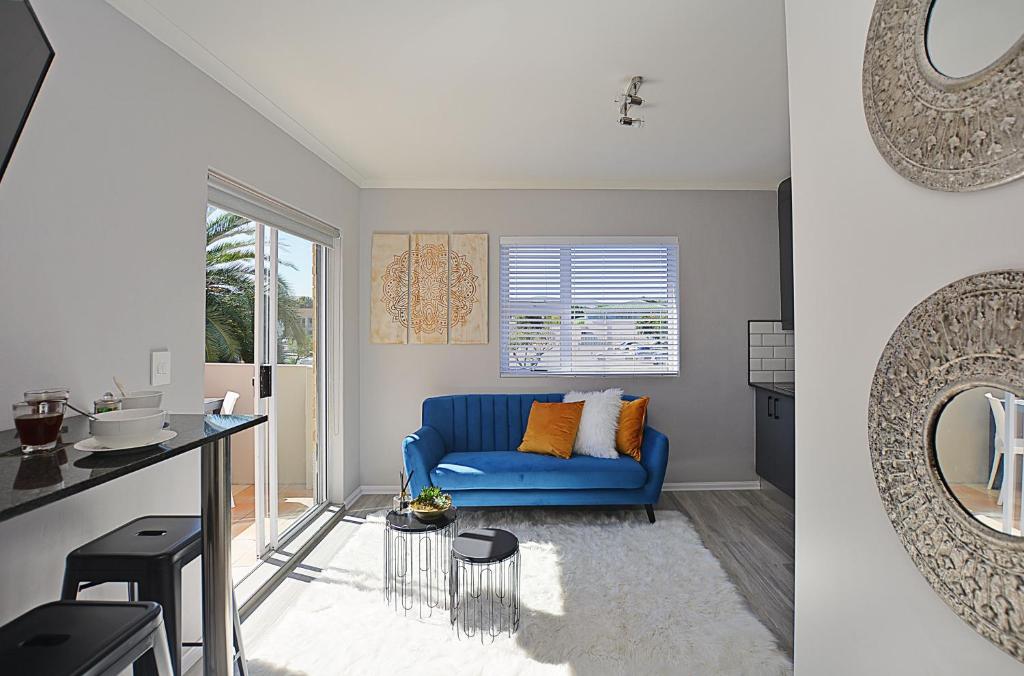 a living room with a blue couch and a mirror at Modern Studio Apartment in Blouberg in Cape Town