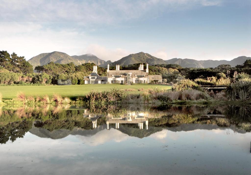 a house next to a lake with mountains in the background at Wharekauhau Country Estate in Wairarapa