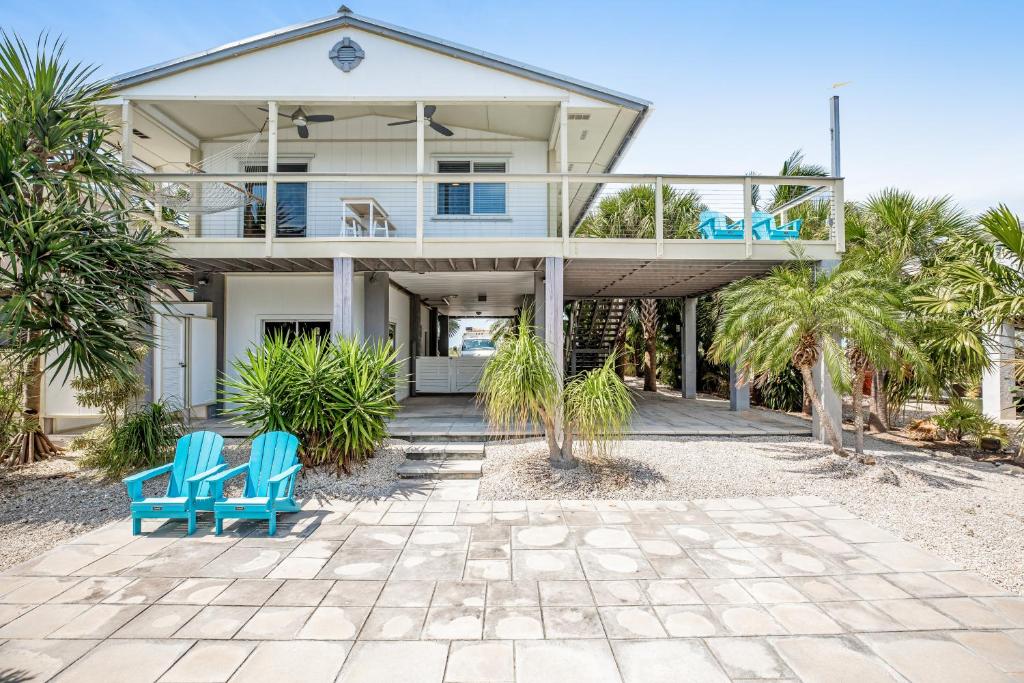 a house on the beach with blue chairs and palm trees at AJ's Hideout in Little Torch Key