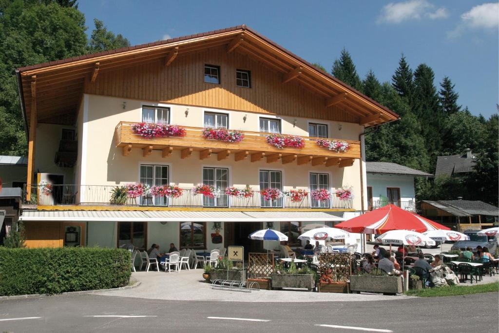 - un grand bâtiment avec un balcon doté de tables et de parasols dans l'établissement 2 Sterne Pension Gasthof ohne Internet, à Steinbach am Attersee