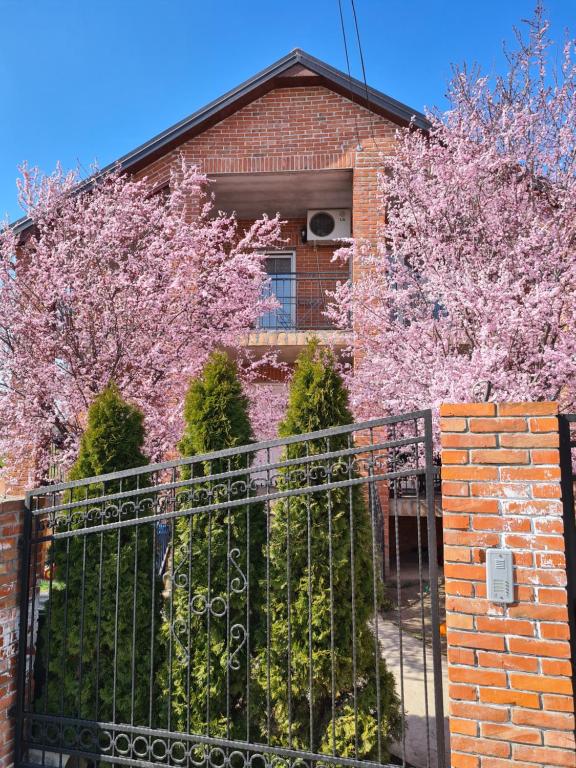 a brick house with a fence and flowering trees at Apartment Ken in Surčin