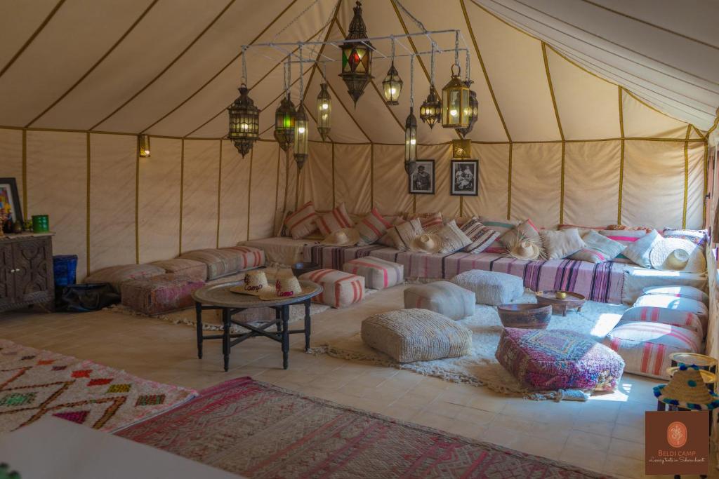 um quarto com sofás e almofadas numa tenda em Beldi camp em Merzouga