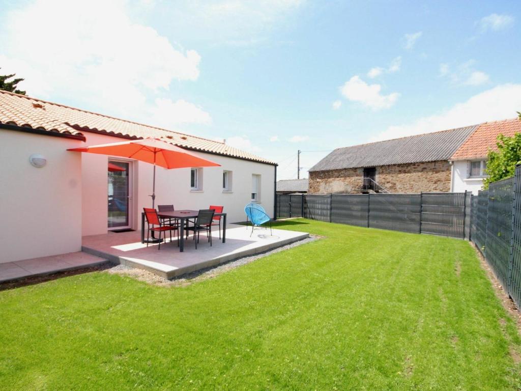 um quintal com uma mesa e cadeiras e um guarda-sol em Gîte Saint-Philbert-de-Grand-Lieu, 3 pièces, 4 personnes - FR-1-306-980 em Saint-Philbert-de-Grand-Lieu