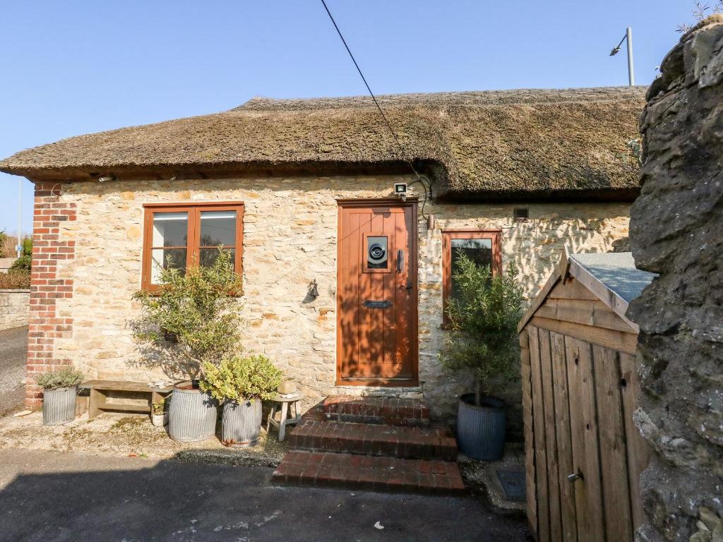 ein Backsteinhaus mit Holztür und einigen Pflanzen in der Unterkunft The Stables in Weymouth