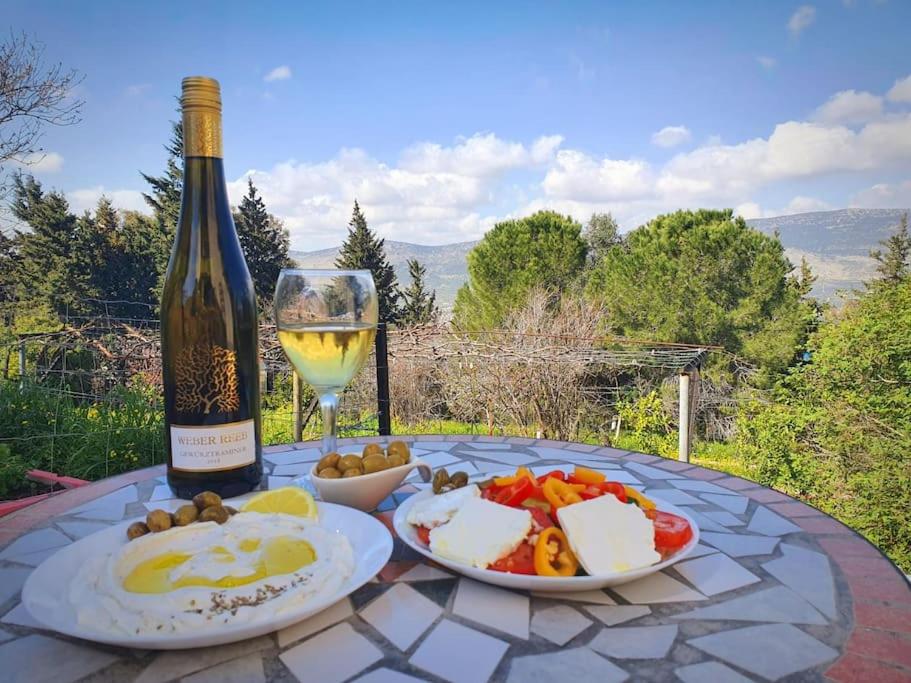 un tavolo con una bottiglia di vino e piatti di cibo di הבית ליד הבוסתן a Mikhmannim