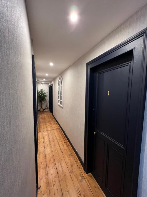 a hallway with a black door and a wooden floor at Chambre D'hôte Villa Maurice in Étretat