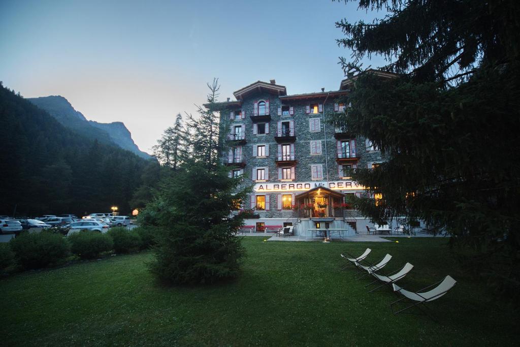 duży budynek z grupą krzeseł w trawie w obiekcie Albergo Monte Cervino w mieście Champoluc