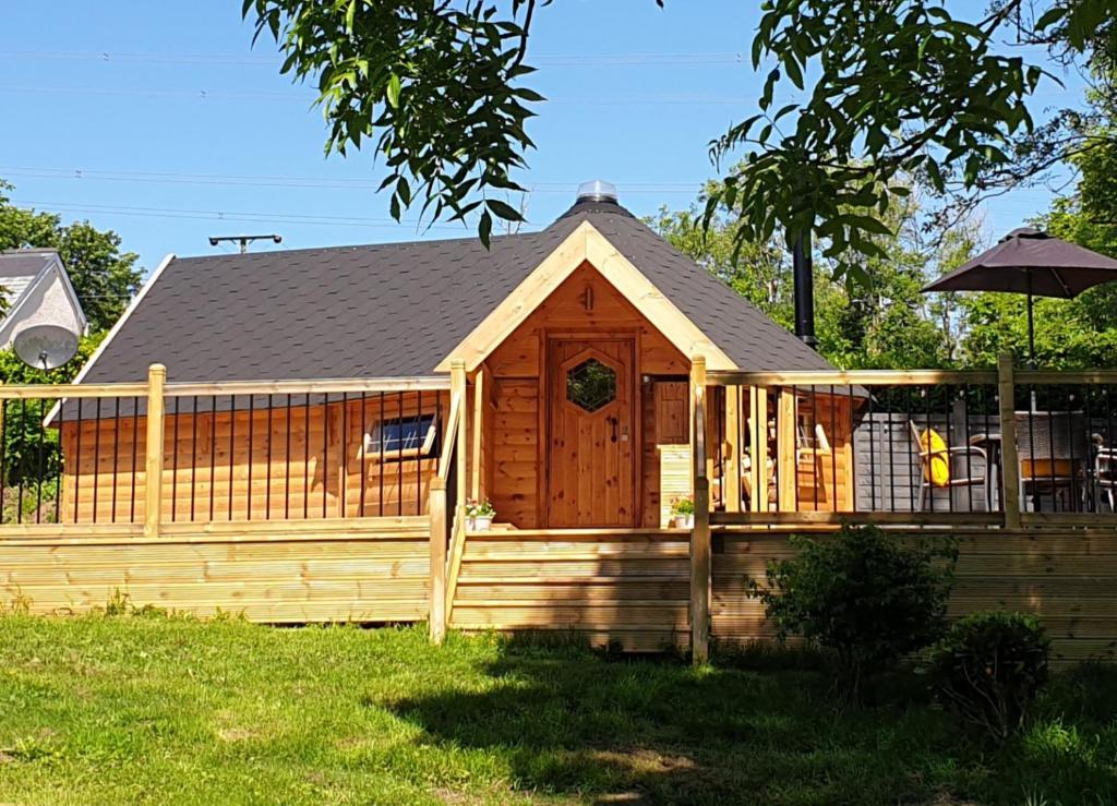 a wooden cabin with a fence and an umbrella at The Hive - Unique log cabin with wood burning stove in Ludchurch