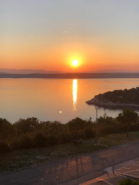a sunset over a body of water with the sun setting at Adria Croatia in Dramalj