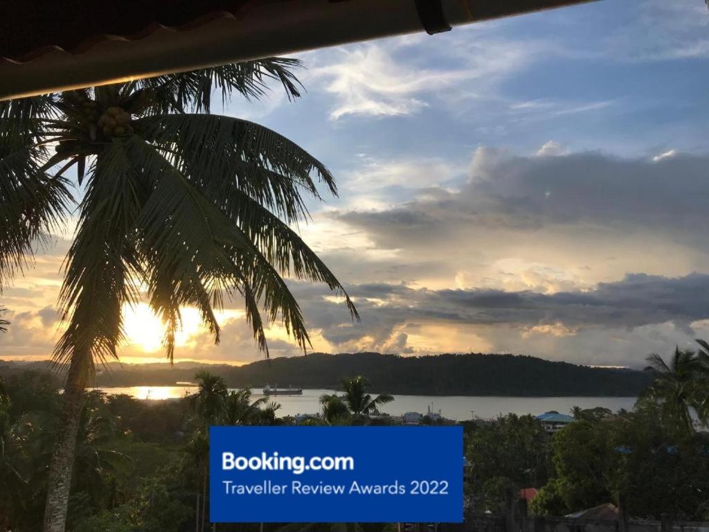 een palmboom met de zonsondergang op de achtergrond bij Ocean Terrace in Port Blair