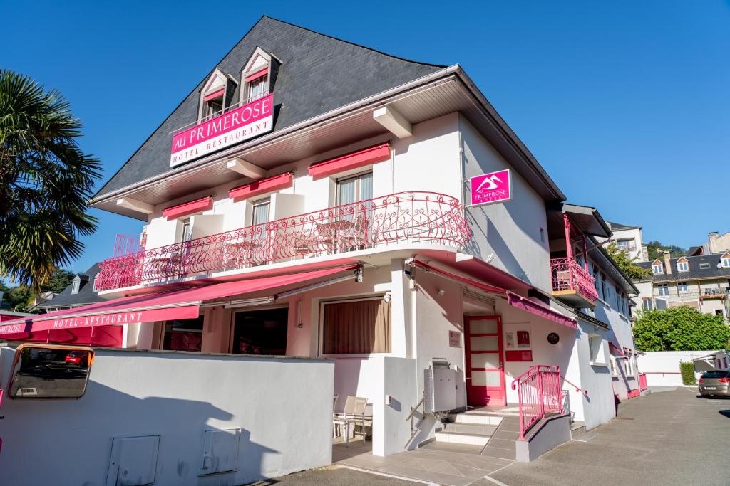 アルジュレス・ガゾストにあるAu Primerose Hôtelの白とピンクの建物(バルコニー付)