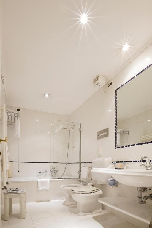 a white bathroom with a tub and a toilet and a sink at Hotel Principe in Venice