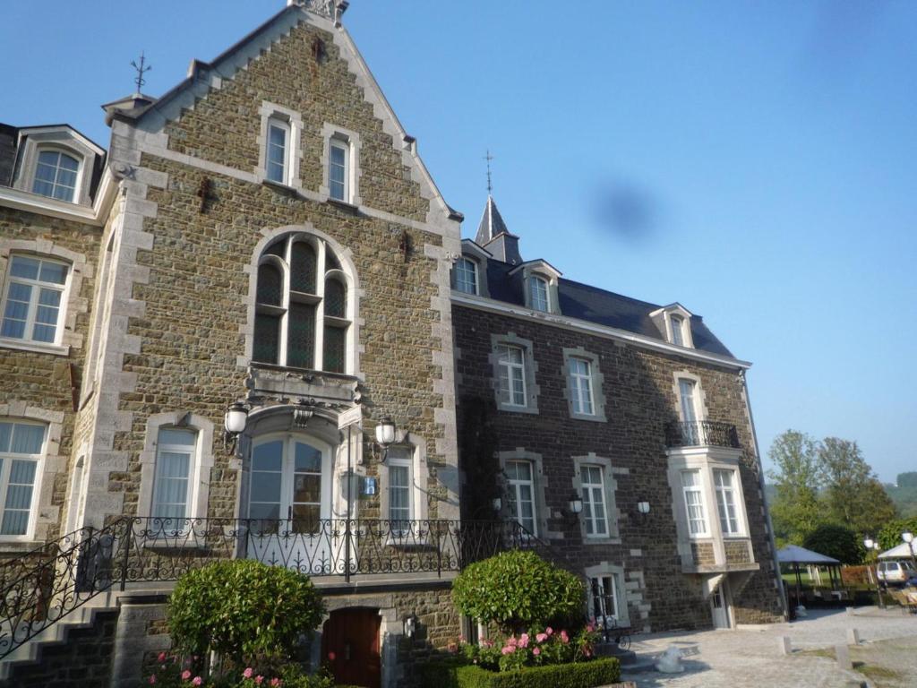 un viejo edificio de ladrillo con flores delante en Le Château de Rendeux en Rendeux