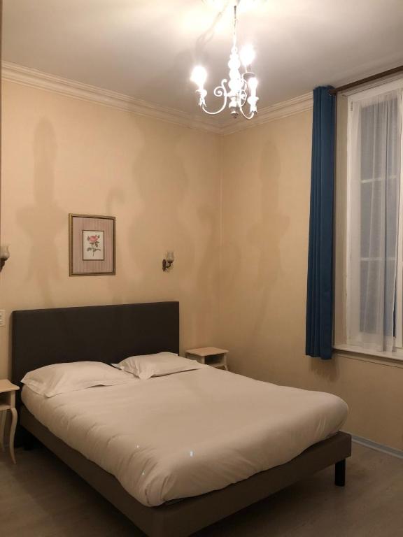 a bedroom with a bed with a chandelier and a window at Hôtel Emilie in Royan